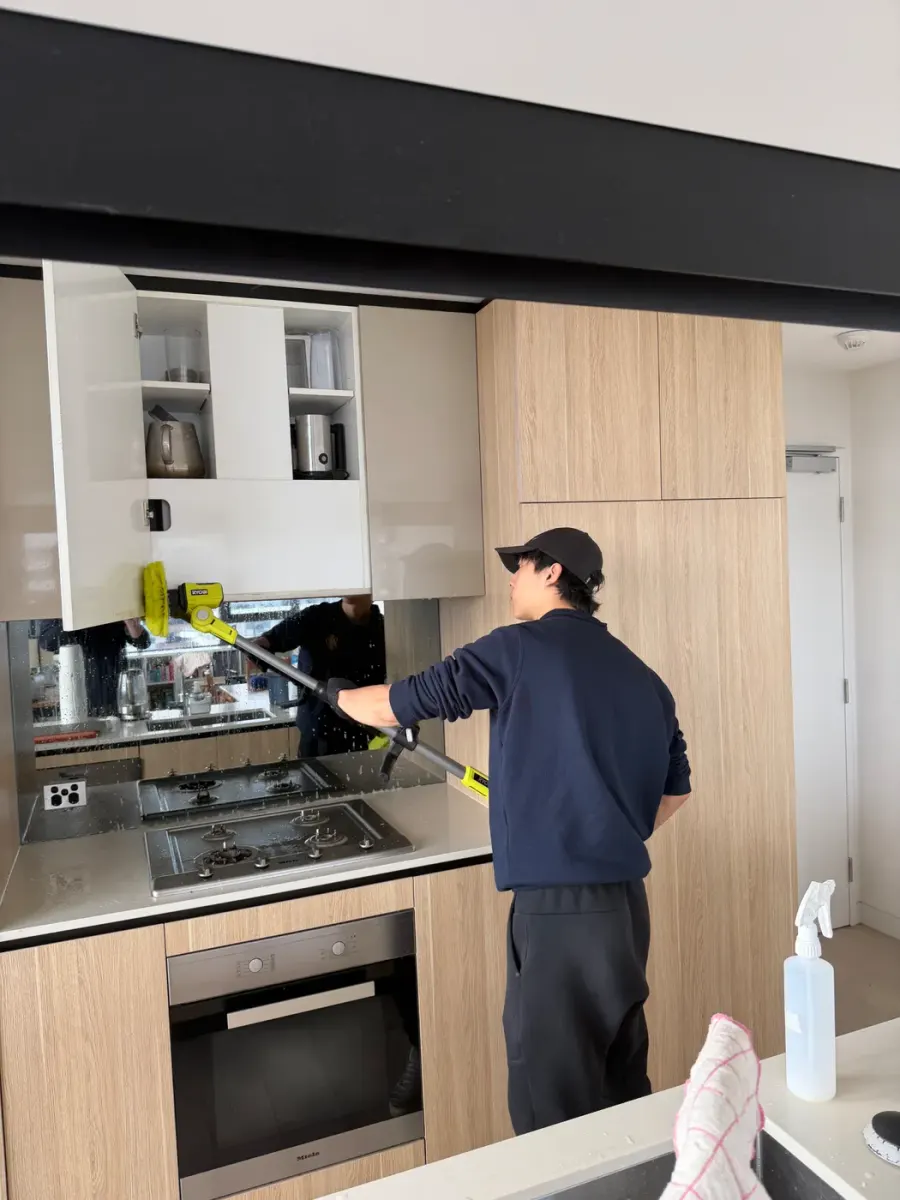 Working a power brush along the kitchen cupboards